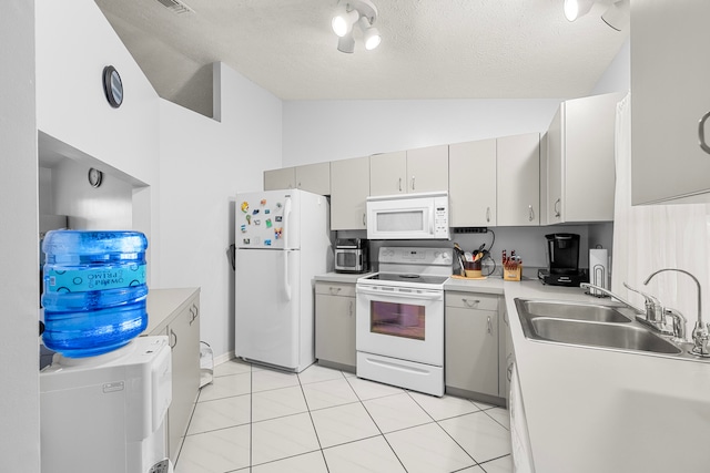 kitchen with sink, a textured ceiling, white appliances, and light tile patterned floors