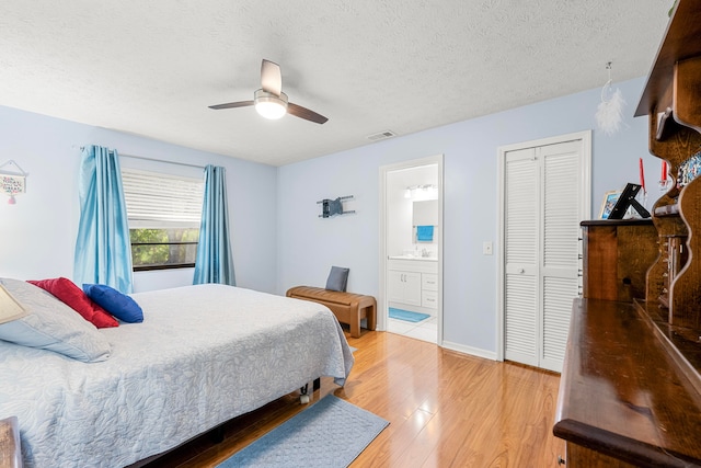 bedroom with ensuite bath, a textured ceiling, a closet, ceiling fan, and hardwood / wood-style flooring