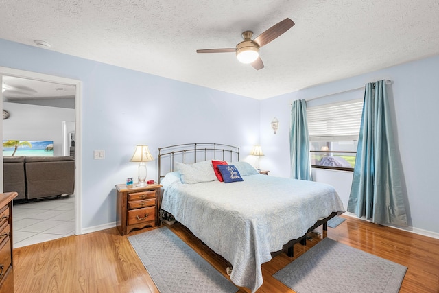 bedroom with light hardwood / wood-style flooring, a textured ceiling, and ceiling fan