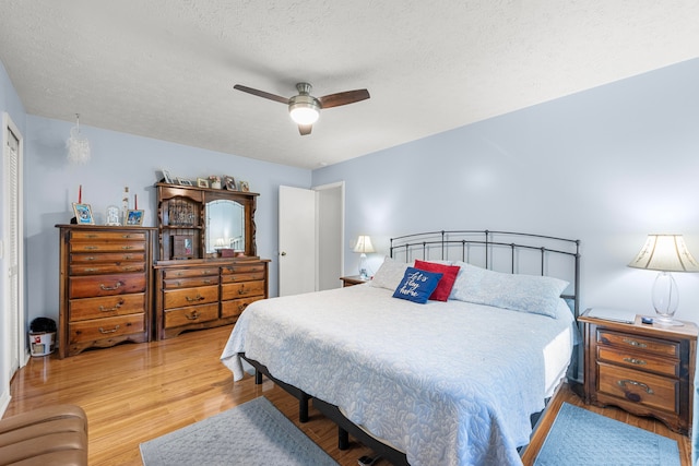 bedroom featuring a closet, a textured ceiling, light wood-type flooring, and ceiling fan