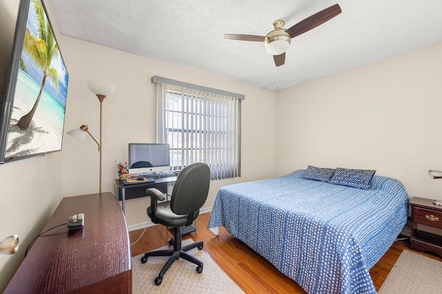 bedroom with ceiling fan, wood-type flooring, and a textured ceiling