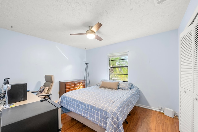 bedroom with a closet, hardwood / wood-style floors, a textured ceiling, and ceiling fan