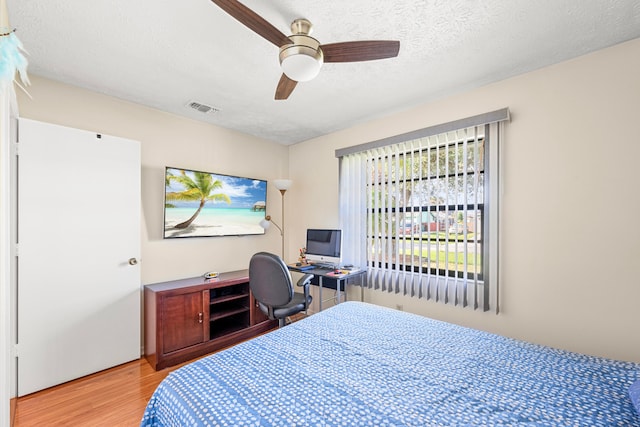 bedroom featuring ceiling fan, hardwood / wood-style flooring, and a textured ceiling