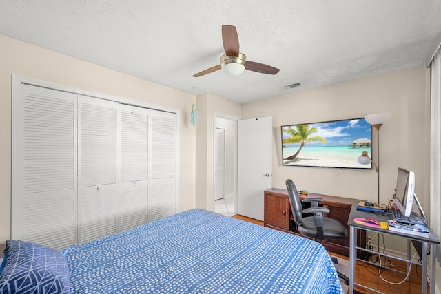 bedroom featuring a closet, a textured ceiling, hardwood / wood-style flooring, and ceiling fan