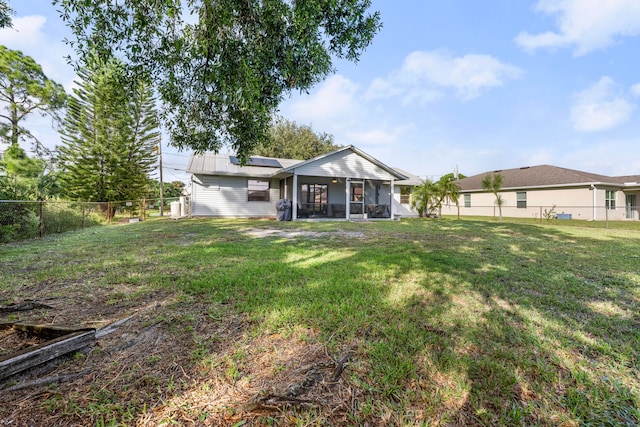 back of property with a lawn and a sunroom