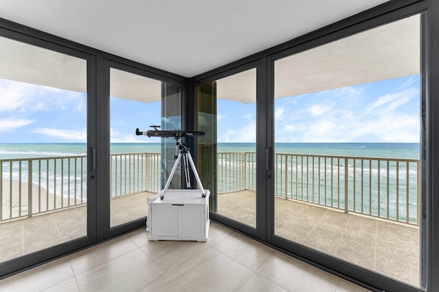 unfurnished sunroom featuring a water view and a view of the beach