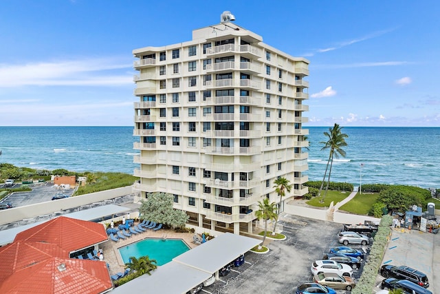 view of building exterior featuring a water view and a community pool