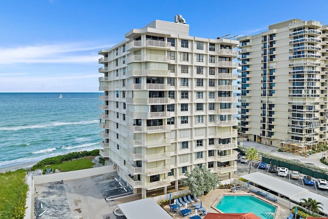 view of building exterior with a community pool and a water view