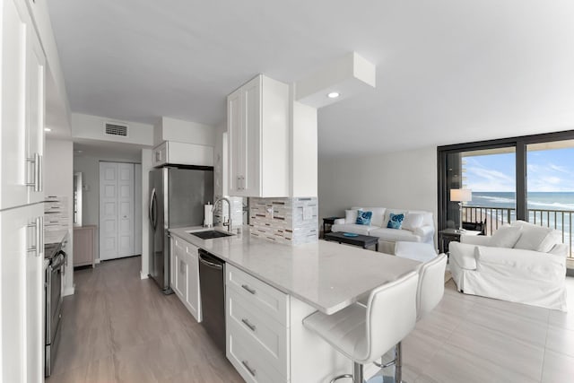 kitchen with backsplash, a water view, white cabinetry, and sink