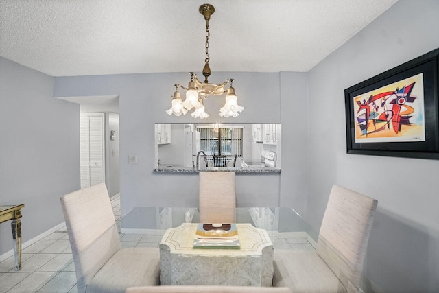 tiled dining room with sink, a textured ceiling, and a chandelier