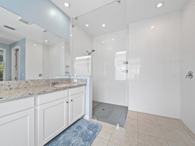 bathroom with vanity, a tile shower, and tile patterned flooring