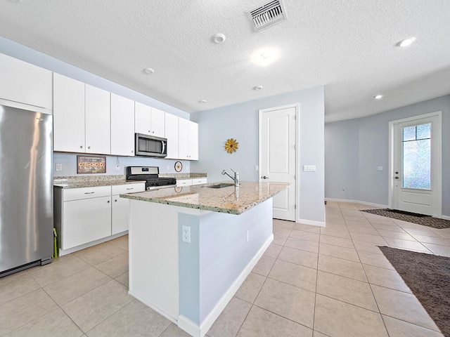 kitchen featuring appliances with stainless steel finishes, white cabinets, sink, and a center island with sink