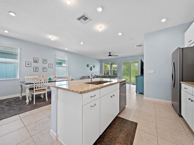 kitchen with white cabinetry, stainless steel appliances, sink, and an island with sink