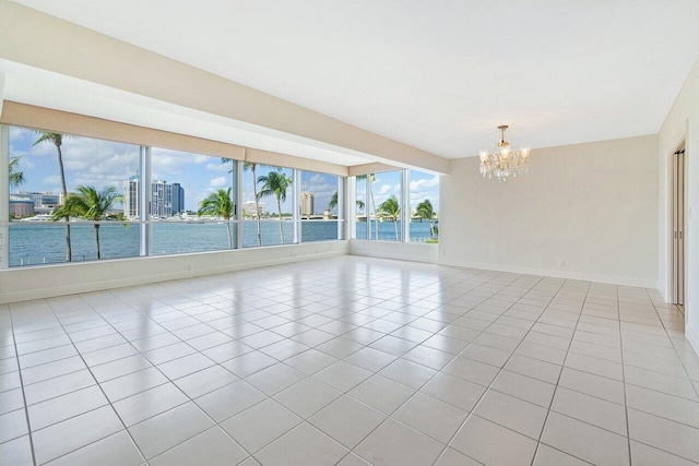 spare room featuring light tile patterned floors, a water view, and an inviting chandelier