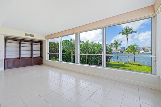 interior space featuring a water view, a healthy amount of sunlight, and light tile patterned flooring