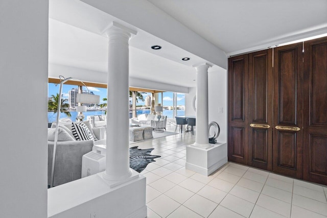 tiled entrance foyer with decorative columns and a water view