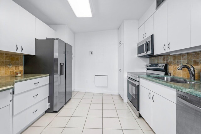 44 Cocoanut Row Unit 120B, Palm Beach, FL 33480 - kitchen featuring appliances with stainless steel finishes, a sink, tasteful backsplash, baseboards, and white cabinetry