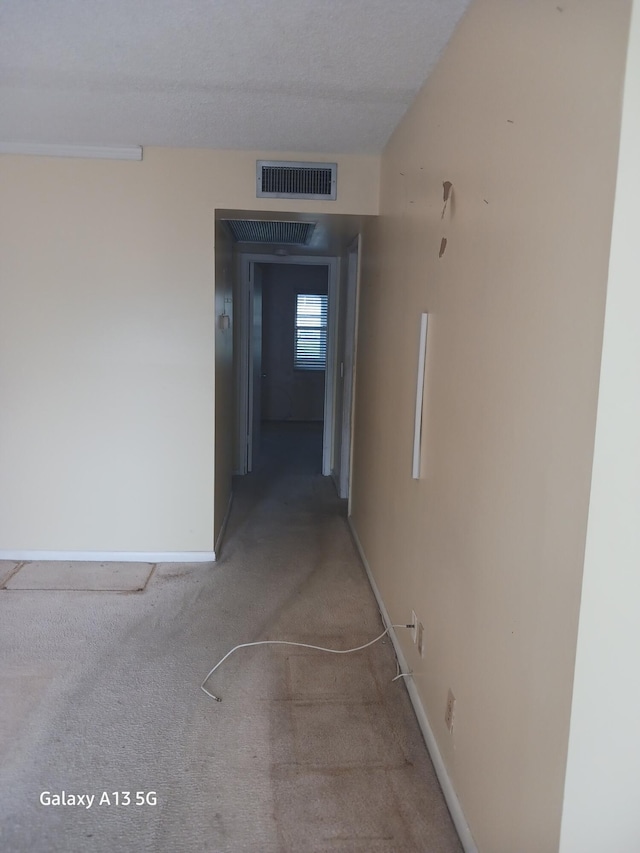 corridor featuring a textured ceiling and carpet