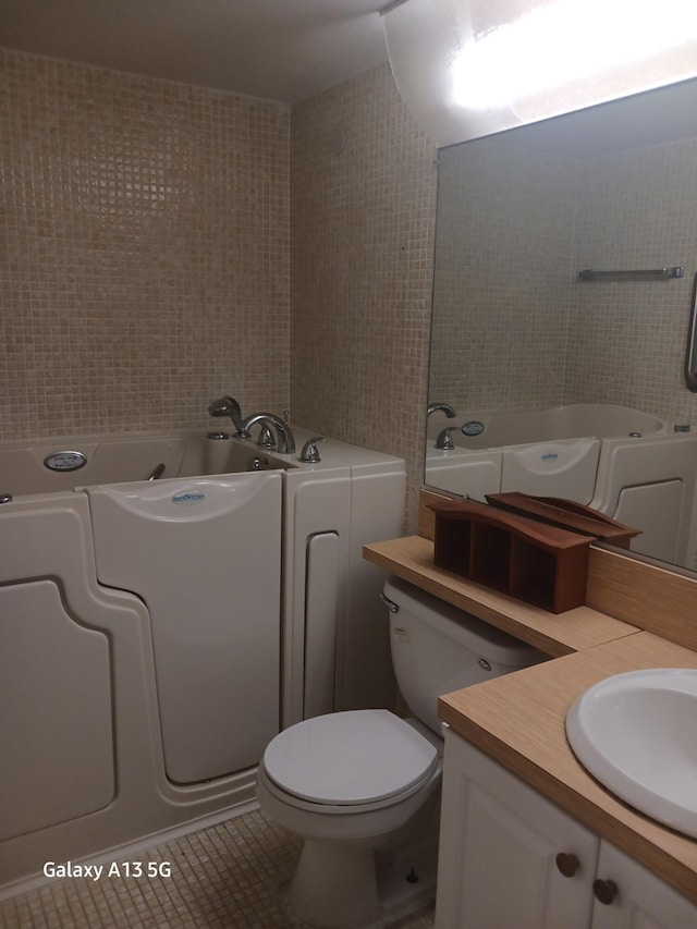 bathroom with toilet, tile patterned floors, tile walls, a bathing tub, and vanity