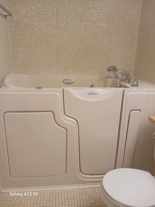 bathroom featuring a shower, toilet, and tile patterned flooring