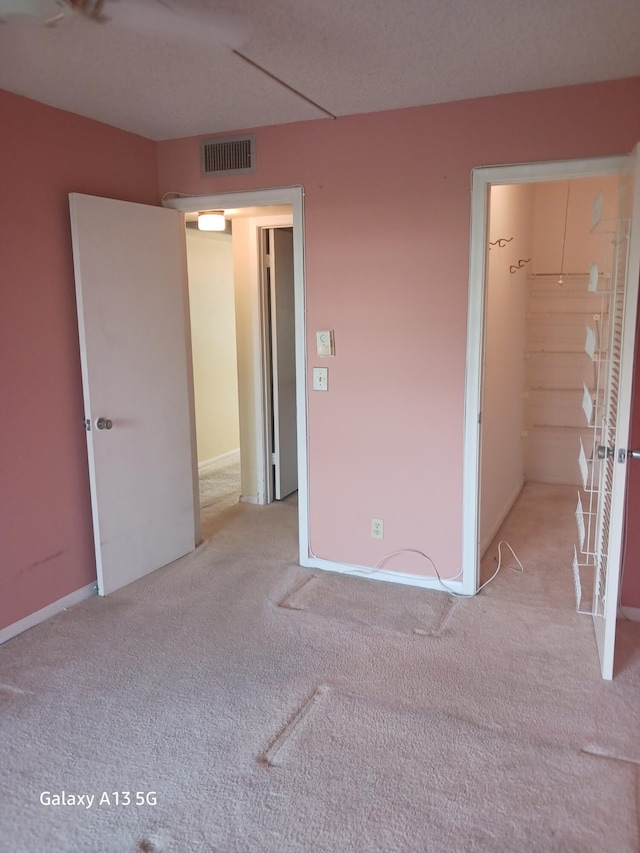 unfurnished bedroom featuring a closet, light carpet, and a walk in closet