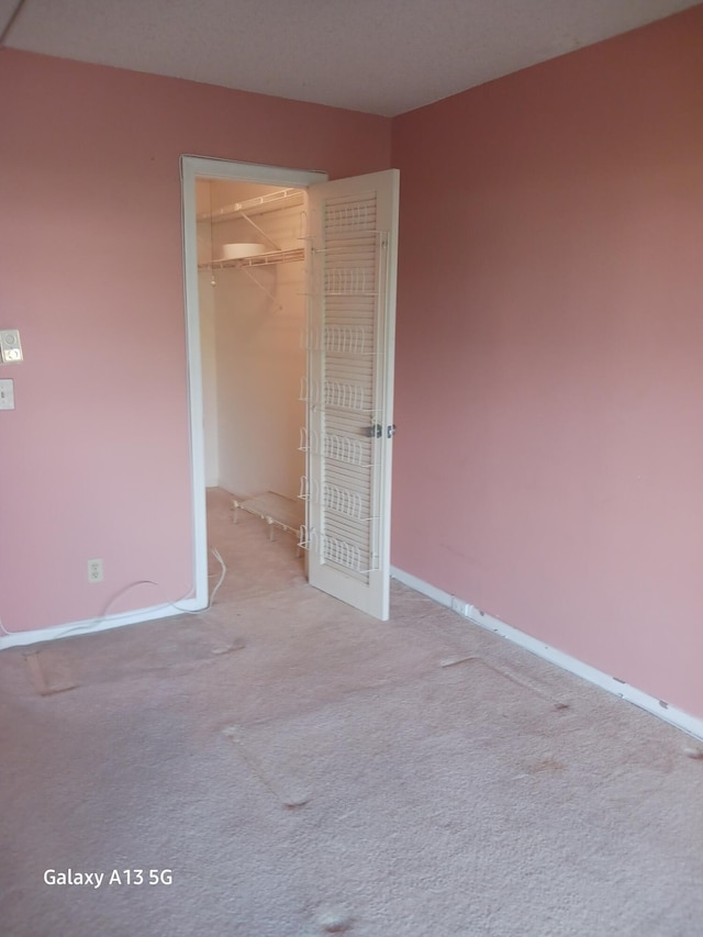 unfurnished bedroom featuring a spacious closet, light carpet, and a closet