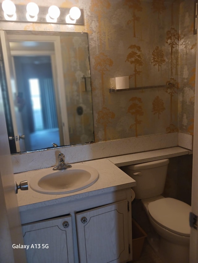 110 Northampton Unit F, West Palm Beach, FL 33417 - half bathroom featuring vanity, toilet, and wallpapered walls