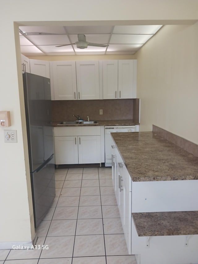 kitchen featuring white cabinetry, light tile patterned flooring, sink, and black refrigerator