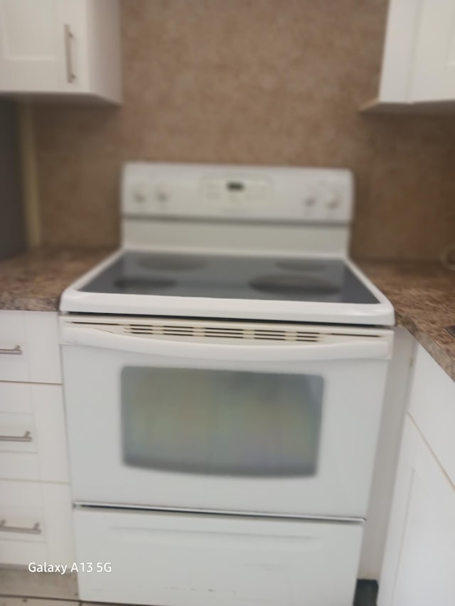 kitchen featuring white electric stove and white cabinets