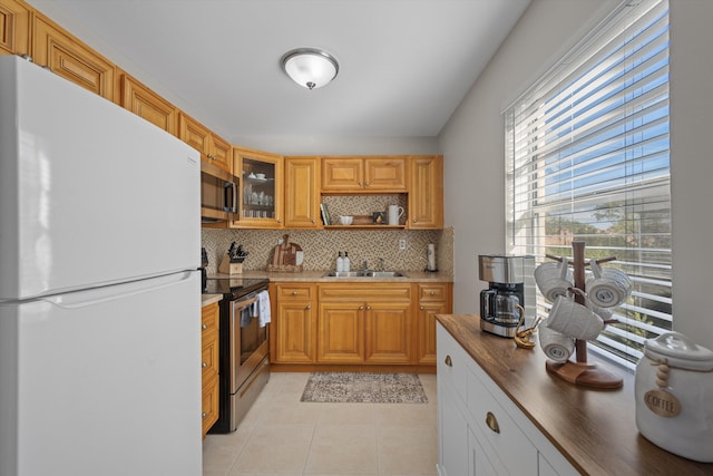 kitchen with sink, wooden counters, decorative backsplash, light tile patterned floors, and appliances with stainless steel finishes