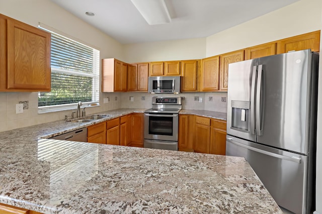 kitchen with sink, decorative backsplash, appliances with stainless steel finishes, light stone counters, and kitchen peninsula