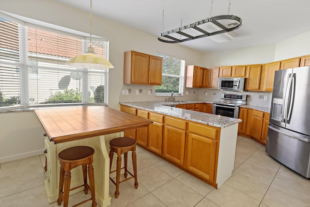 kitchen featuring light stone countertops, sink, backsplash, light tile patterned floors, and appliances with stainless steel finishes