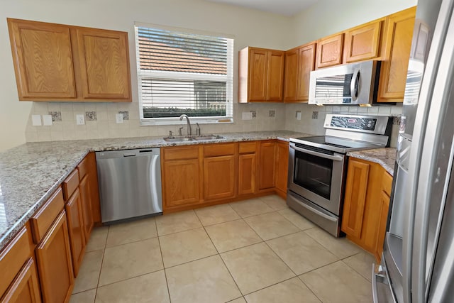 kitchen featuring decorative backsplash, sink, light tile patterned floors, and appliances with stainless steel finishes