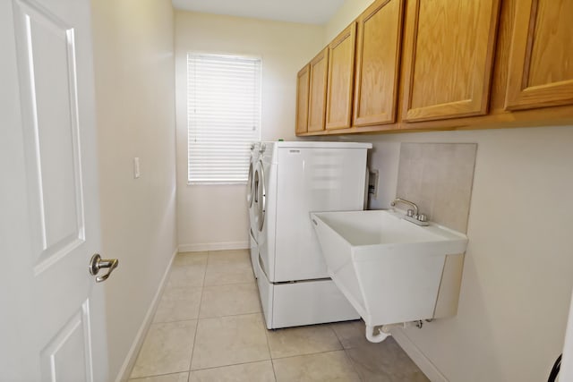 laundry room featuring cabinets, light tile patterned floors, washer and clothes dryer, and sink