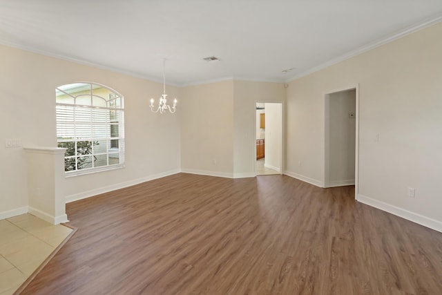 spare room featuring wood-type flooring, an inviting chandelier, and ornamental molding