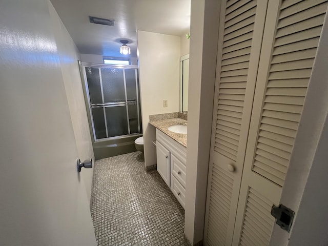 full bathroom featuring tile patterned flooring, vanity, bath / shower combo with glass door, and toilet