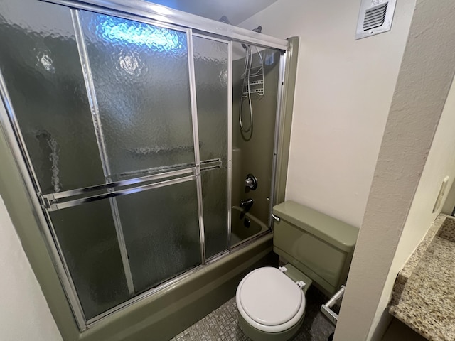 bathroom featuring tile patterned flooring, toilet, and shower / bath combination with glass door