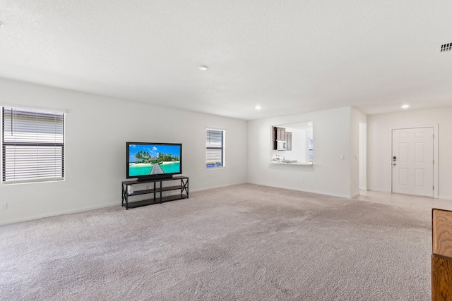 unfurnished living room featuring light colored carpet and a textured ceiling