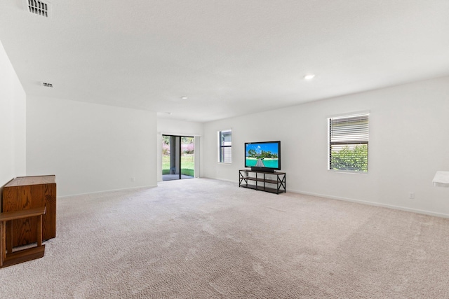 unfurnished living room with a wealth of natural light and light carpet