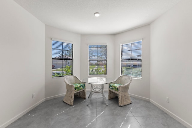 living area with a healthy amount of sunlight, light tile patterned floors, and a textured ceiling