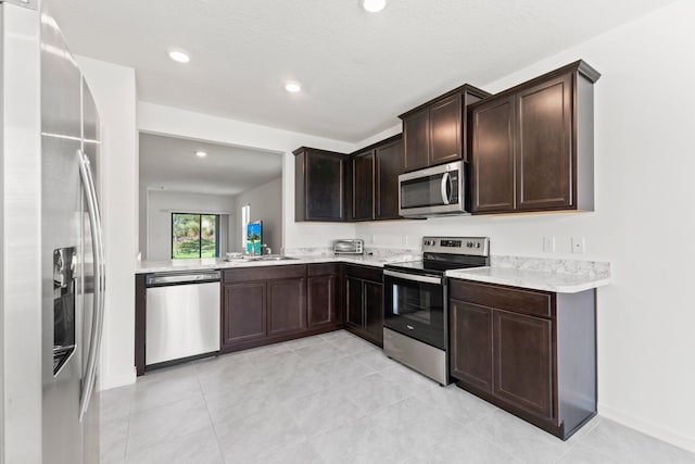 kitchen featuring a textured ceiling, dark brown cabinetry, sink, and appliances with stainless steel finishes