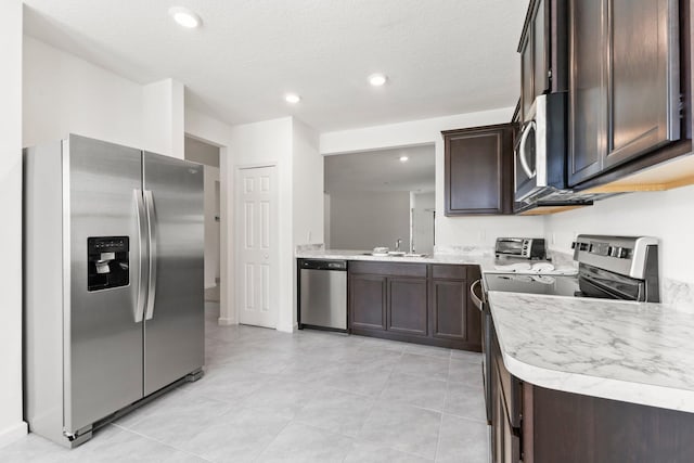 kitchen with appliances with stainless steel finishes, dark brown cabinetry, a textured ceiling, sink, and light tile patterned flooring