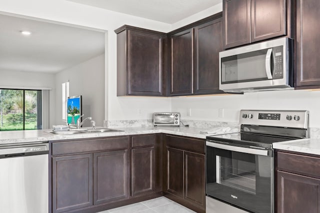 kitchen featuring dark brown cabinetry, light stone countertops, sink, stainless steel appliances, and light tile patterned flooring