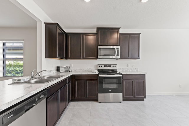 kitchen with a textured ceiling, dark brown cabinets, sink, and appliances with stainless steel finishes