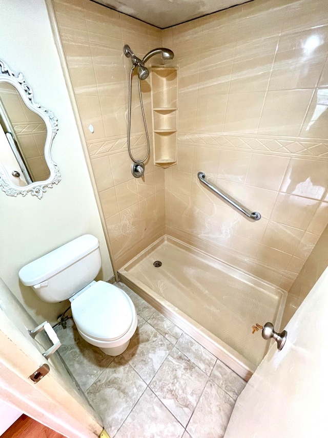 bathroom featuring a tile shower, tile patterned floors, and toilet