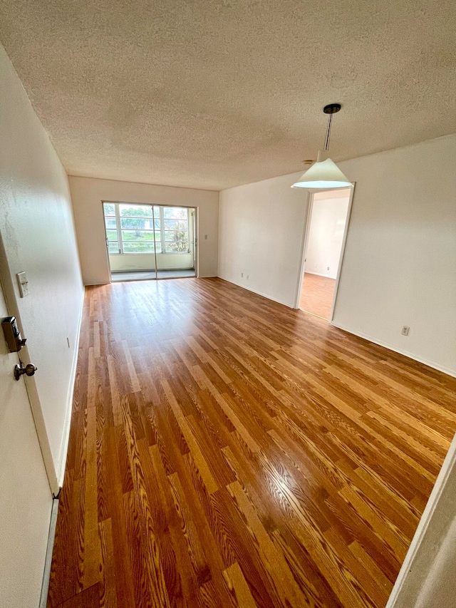 empty room with a textured ceiling and hardwood / wood-style flooring