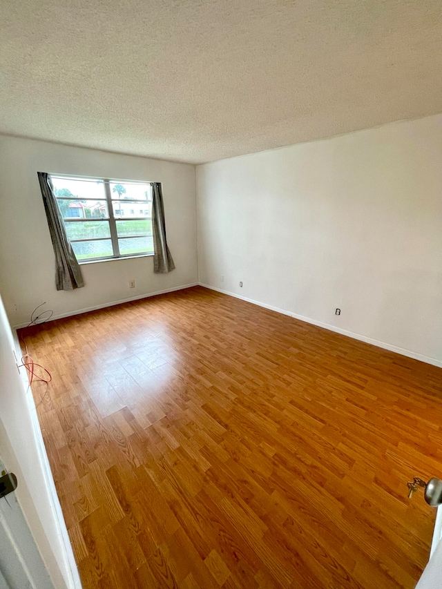 spare room featuring wood-type flooring and a textured ceiling