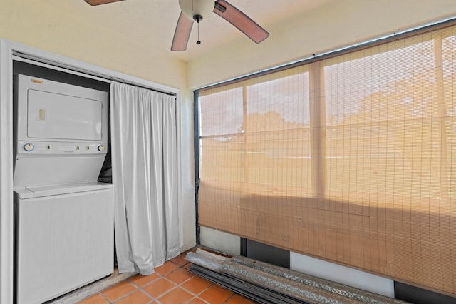 laundry room featuring ceiling fan, light tile patterned floors, and stacked washer and clothes dryer