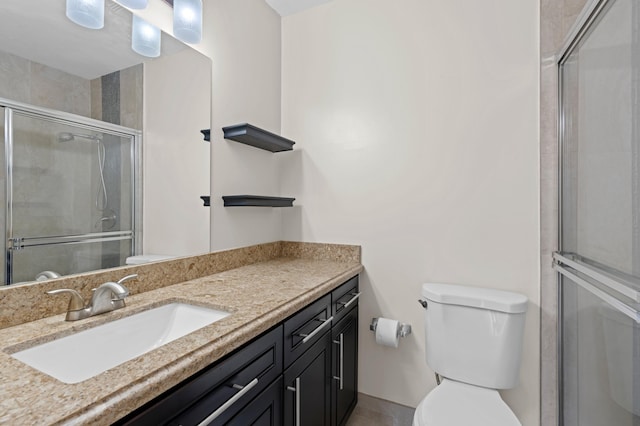 bathroom featuring a shower with door, toilet, and vanity