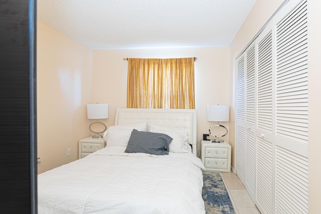 bedroom featuring a closet, a textured ceiling, and light tile patterned floors